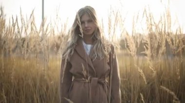 Sarışın kadın ile yüksek çim alanda ve kameraya bakarak ceket