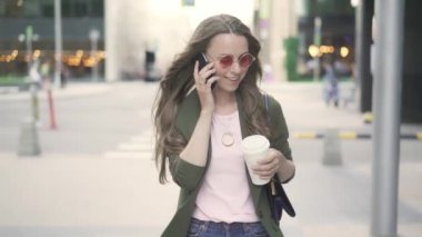 Yürüyüş ve smartphone içinde konuşurken güzel beyaz kadın şehir düşmek