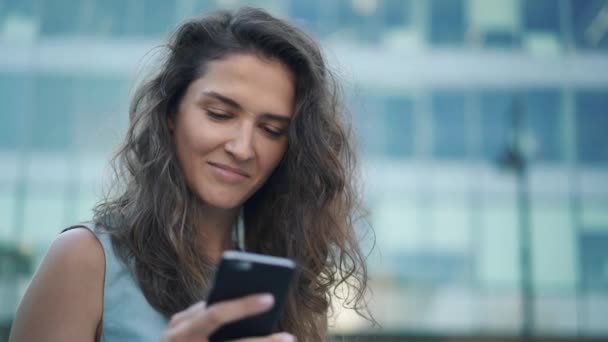 Mooi jong meisje in blauwe jurk jatten van haar smartphone scherm in het centrum — Stockvideo