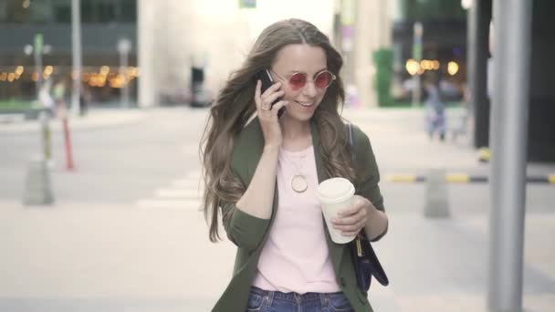 Hermosa mujer caucásica caminando y hablando en el teléfono inteligente en la ciudad de otoño — Vídeos de Stock