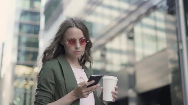Kvinna som står i falla staden gatan webbsurfning och dricka kaffe — Stockvideo