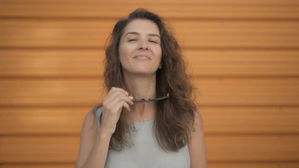 Hermosa joven mujer quitándose las gafas de sol, sonriendo y riendo — Vídeo de stock