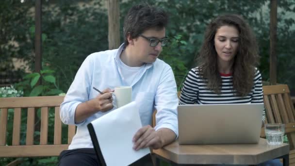 Unga medarbetare som arbetar i sommarcafé med laptop och Urklipp — Stockvideo