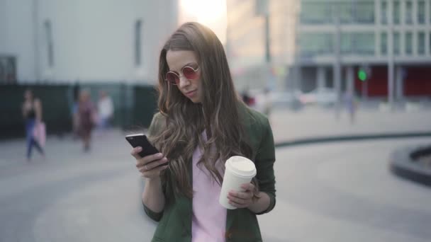 가 서 커피와 함께 젊은 여성을 매력적이 고 그녀의 스마트폰을 사용 하 여 — 비디오