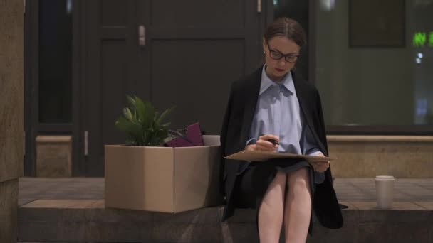 Businesswoman writing looking for a job cardboard sign in street — Stock Video