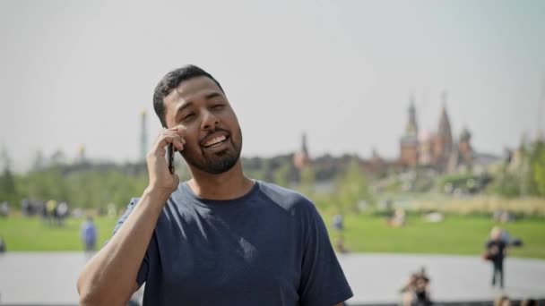Leende ung man pratar telefon i Moskva på solig dag — Stockvideo