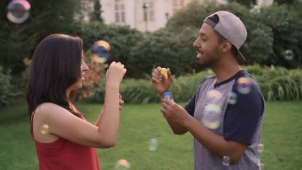 Man en vrouw blazen van zeepbellen op elkaar op zomerdag — Stockvideo