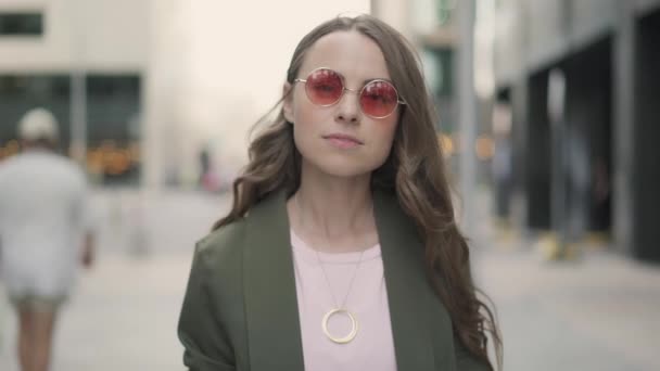 Hermosa joven mirando hacia arriba y sonriendo de pie en la calle de la ciudad — Vídeos de Stock