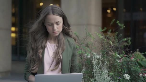 Серйозна бізнес-леді, що працює з ноутбуком зовні — стокове відео