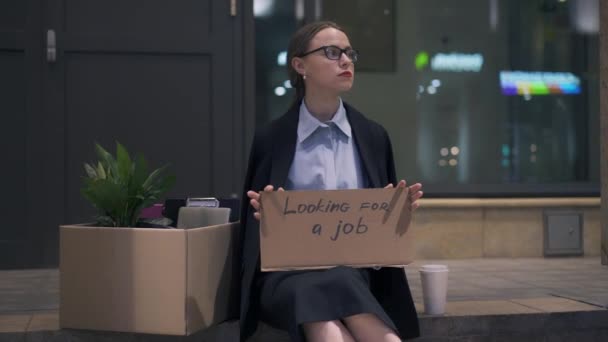 Verärgerte Frau sitzt mit Pappe auf der Suche nach einem Jobschild auf der Straße — Stockvideo