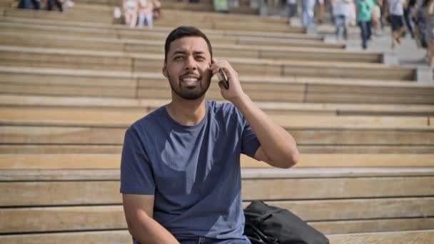 Улыбающийся латиноамериканец разговаривает по телефону снаружи — стоковое видео