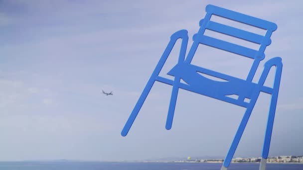 Avión volando junto a la estatua de la silla azul en Niza, Francia — Vídeo de stock