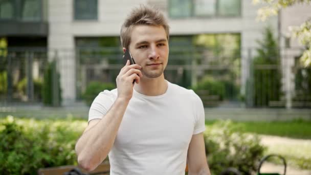 Jeune homme parlant sur smartphone dans la rue, ne pas croire ce qu'il entend — Video