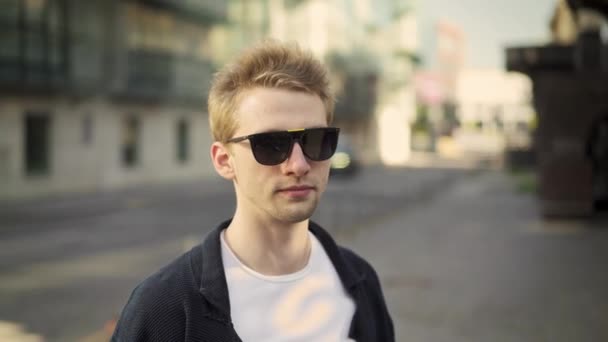 Blond young man taking off sunglasses and blinking — Stock Video