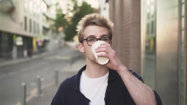 Homem de óculos bebendo café e olhando para o smartphone — Vídeo de Stock