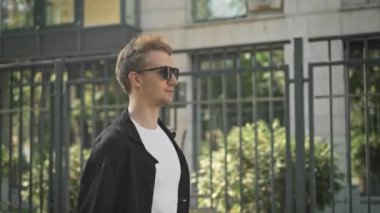 Yürüyüş boyunca çit ve manifatura güneş gözlüğü ciddi genç adam