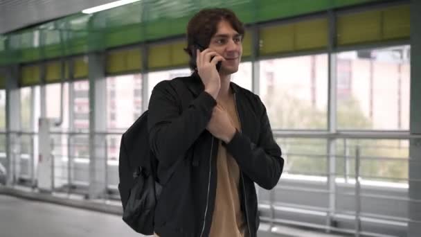 身穿黑色夹克的男子在智能手机上行走和说话 — 图库视频影像