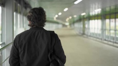 Tünelde yürüyen siyah ceketli adamı arka görünümü