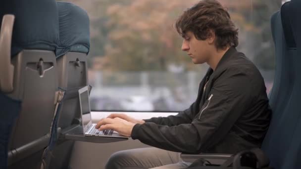 Człowiek, wpisując na laptopie w pociągu — Wideo stockowe