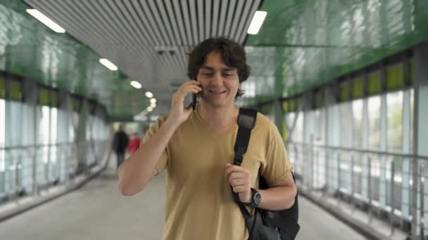 Leende ung man gå och prata på smartphone — Stockvideo