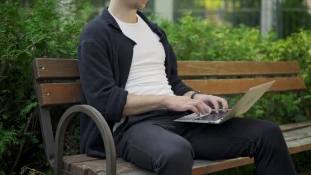 Unrecognizable man typing on laptop sitting on bench — Stock Video