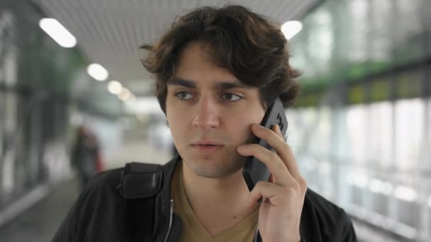 Портрет молодого человека, разговаривающего по телефону в тоннеле — стоковое видео