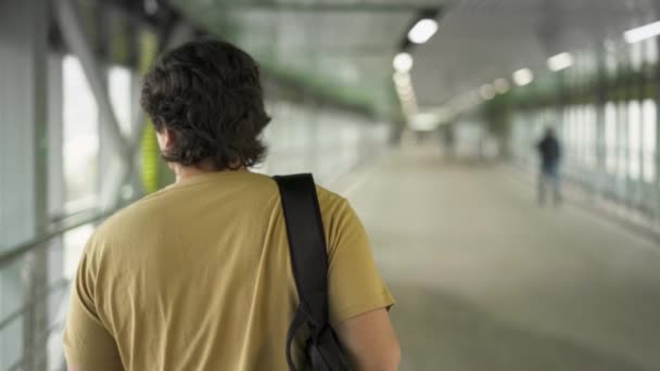 Vista trasera del hombre en camiseta beige caminando en túnel — Vídeo de stock