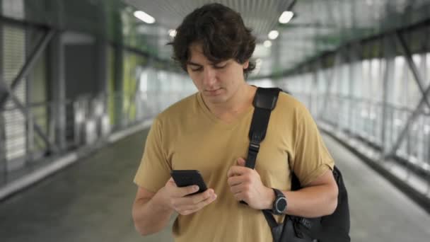 Guapo joven caminando y navegando por la web en su teléfono inteligente — Vídeo de stock