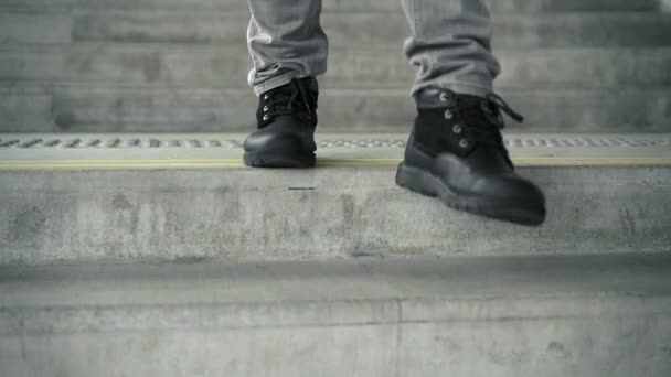Hombre con botas negras bajando las escaleras — Vídeos de Stock