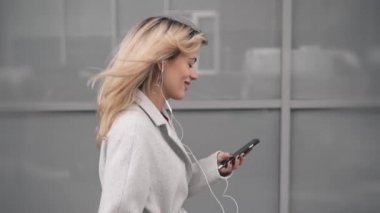 Sokakta yürürken müzik dinlemek montlu sarışın kadın