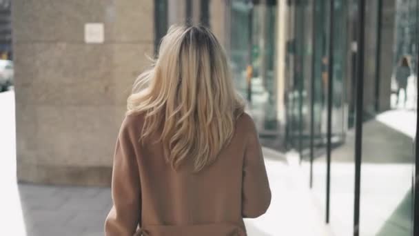 Vue arrière de la jeune femme en manteau beige marchant dans la rue d'automne — Video