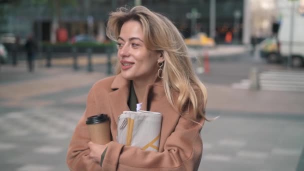 Blonde vrouw met koffie met koude rillingen in najaar straat — Stockvideo