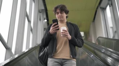 Ciddi genç adam web sörf yürüyen merdiven