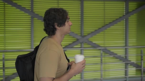 Vista lateral del hombre con mochila caminando con café — Vídeos de Stock