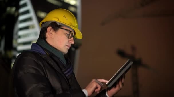 Medium shot profile of architect moving forward in yellow helmet holding a tablet — Stock Video