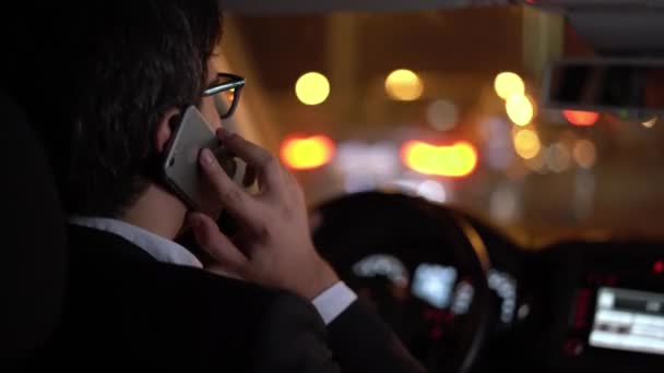 Homme d'affaires conduisant une voiture dans la ville de nuit parler au téléphone — Video