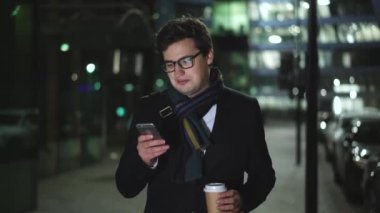 Bir telefon ve bir yudum kahve alarak gece yolda yürüyen adam tutar