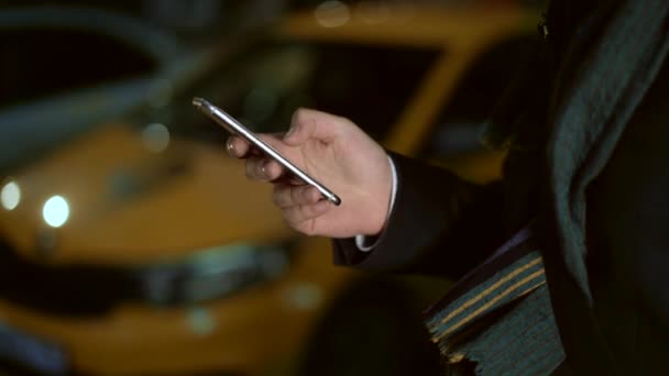 Primer plano de mano masculina con un teléfono. Taxi en el bakcground — Vídeos de Stock