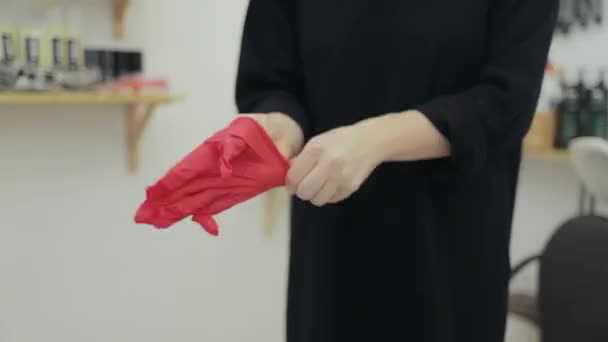 Peluquería poniéndose un guante rojo — Vídeos de Stock