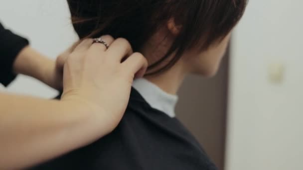 Eine Friseurin trägt einen weißen Kragen um den Hals der Frau — Stockvideo
