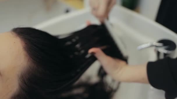 Κοντινό πλάνο του κομμωτή που χτενίζει τα μαλλιά μετά την βαφή μαλλιών — Αρχείο Βίντεο