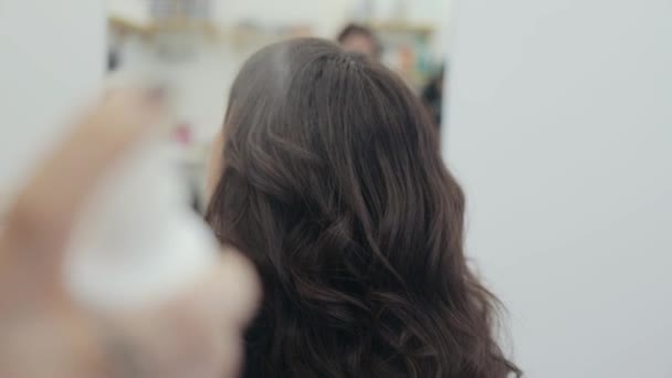 Hairdresser sprankling spray for curled hair of woman in salon — Stock Video