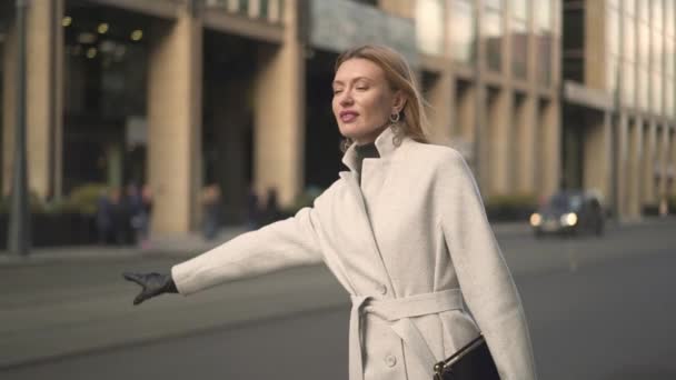 Attractive woman holding a cup of coffee waiting for the taxi — Stock Video