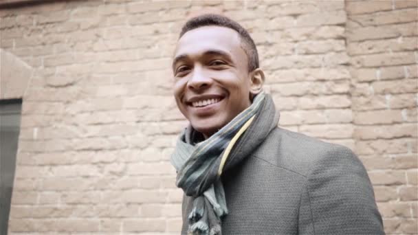 Portrait shot of handsome smiling, winking and saying yes African American man in a coat and a scarf. Handheld slow motion shot. — Stock Video