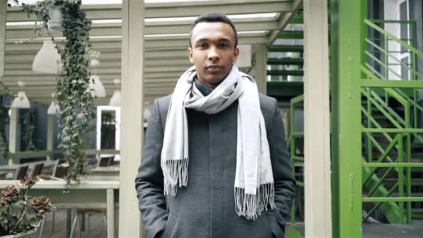 Medium shot of handsome African American man who is wearing a coat and a scarf. Handheld slow motion portrait shot. — Stock Video