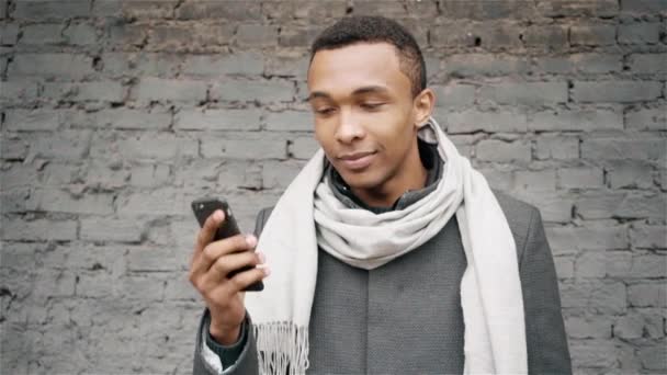 Портрет замедленной съемки афро-американского человека, разговаривающего по телефону. Красивый афро-американец в пальто и шарфе говорит по мобильному телефону . — стоковое видео