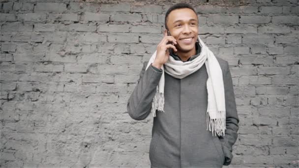 Κατακόρυφος βολή της αφρο-αμερικανικό άνθρωπος που μιλάει στο τηλέφωνο. Όμορφος αφροαμερικανός άντρας σε ένα παλτό και μαντήλι μιλώντας στο κινητό τηλέφωνο. — Αρχείο Βίντεο