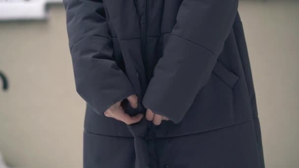 Уповільнення жінки, що застібає зимове пальто на відкритому повітрі — стокове відео