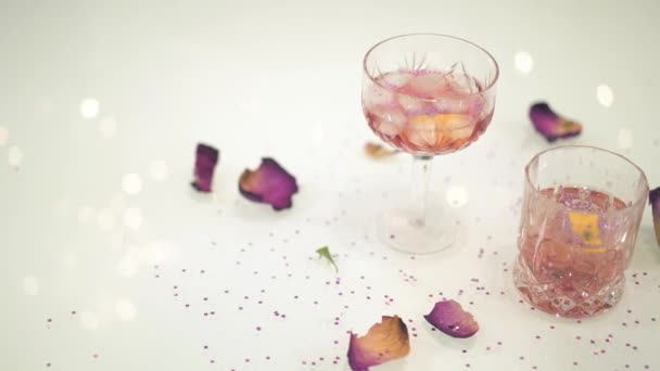 Due cocktail con petali di limone e fiori sul tavolo bianco con riflesso lampeggiante — Video Stock