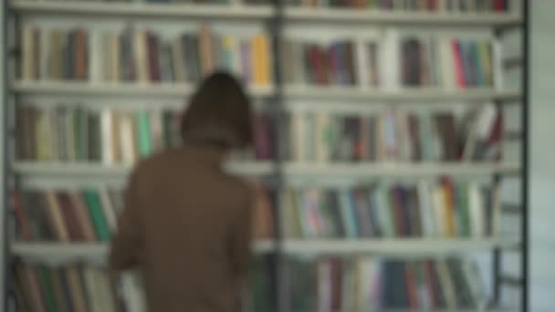 Colpo sfocato di studente di sesso maschile sullo sfondo di librerie in biblioteca — Video Stock